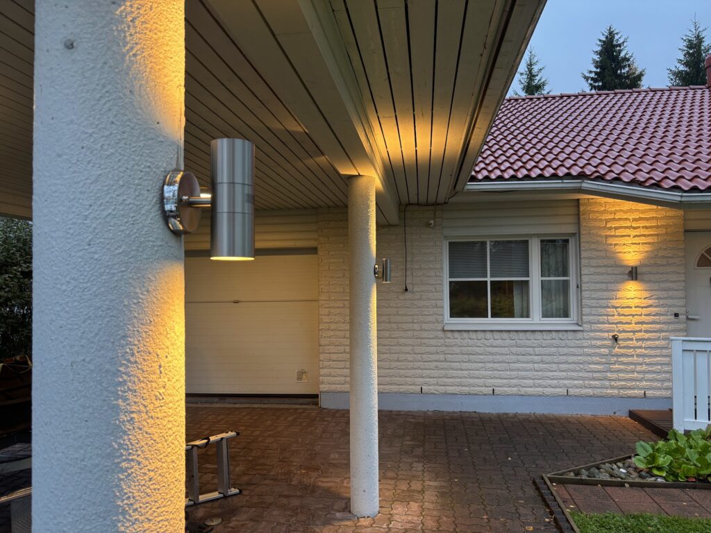 Omakotitalon katoksen ulkovalaistus, valaisimet pilareissa illalla
